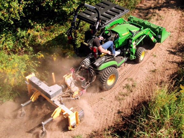 Nortec Raptor Compact Power Rake on Dirt Trail behind John Deere 1025R